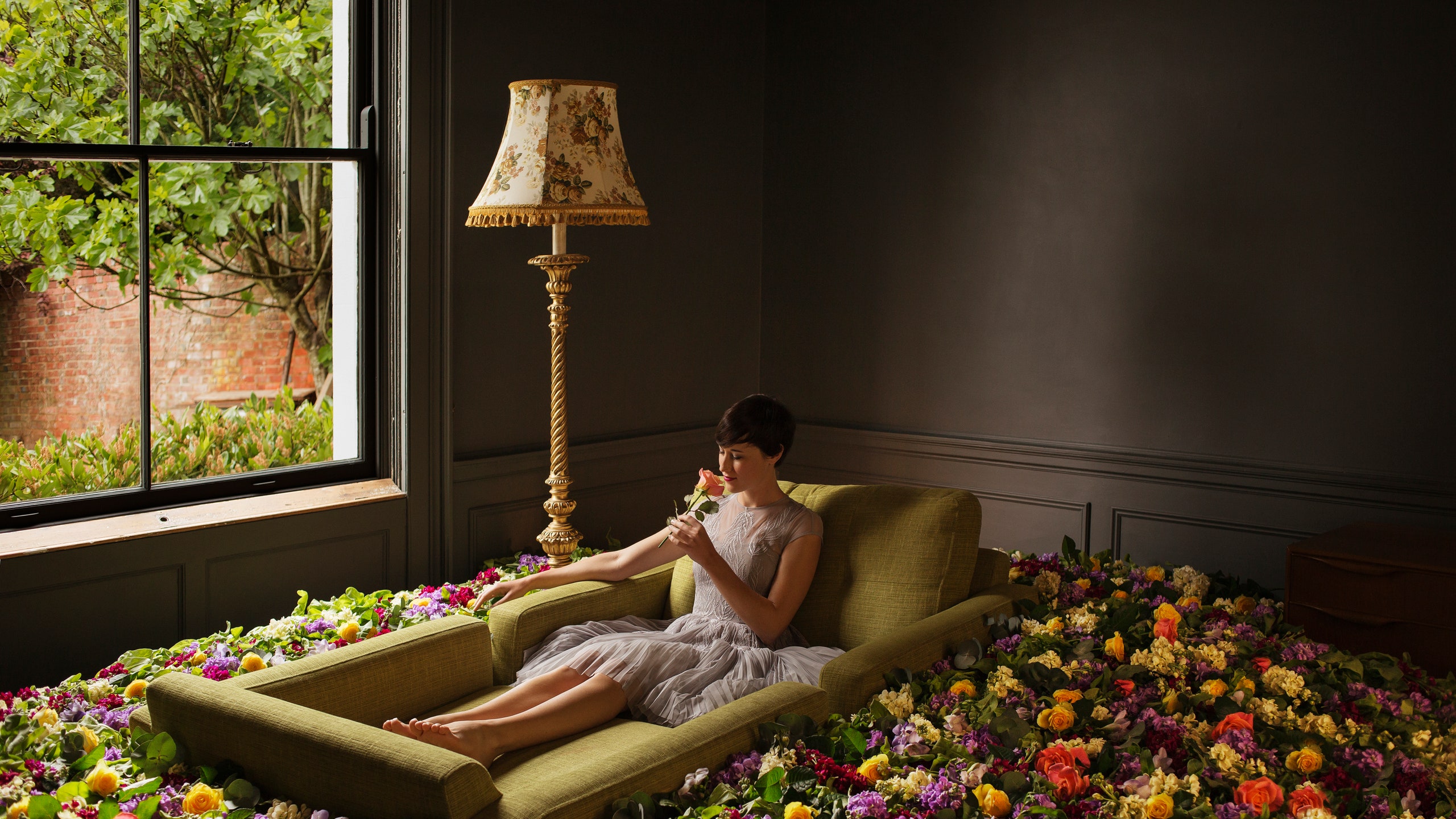 Женщина сидящая на диване в цветах